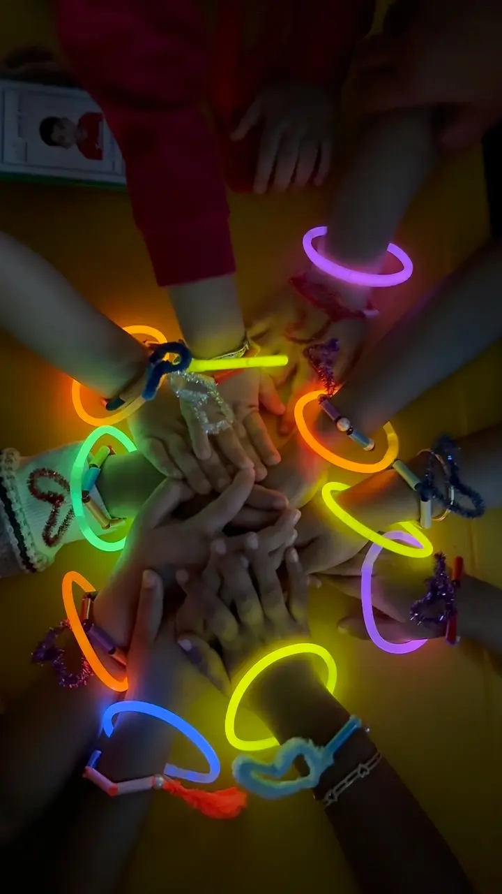Children’s hands wearing neon glow bracelets in a darkened room