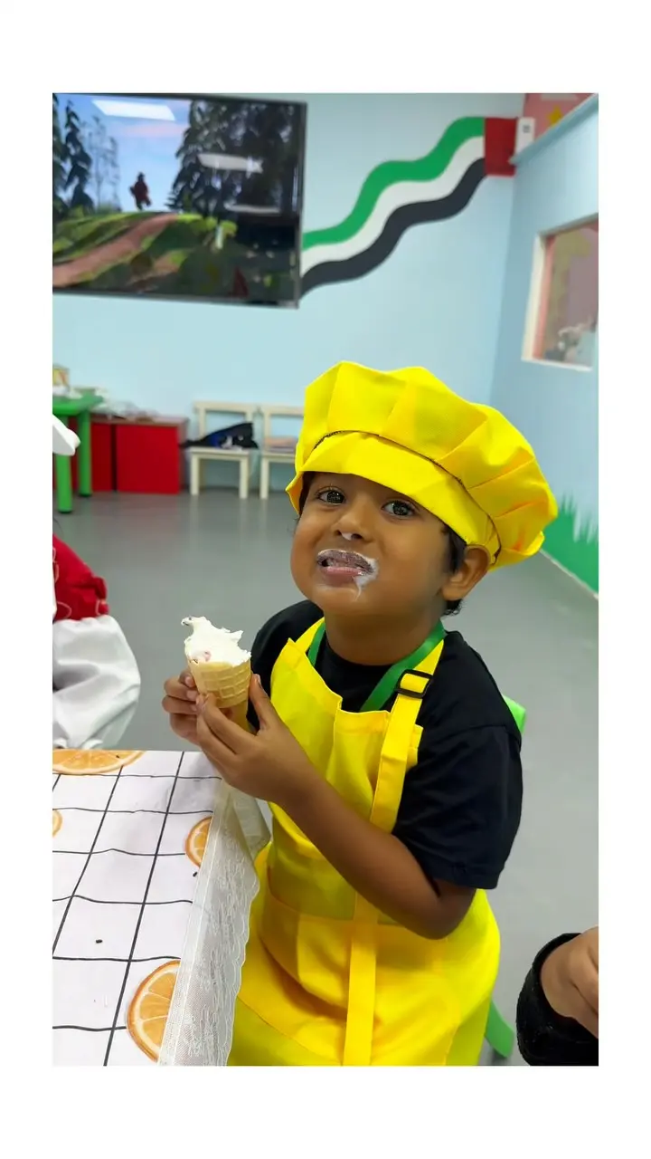 A child in a yellow chef’s hat holding an ice-cream cone