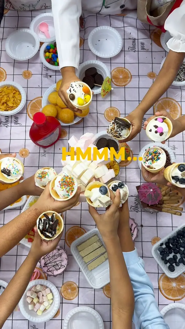 Children’s hands decorating ice-cream cups with toppings