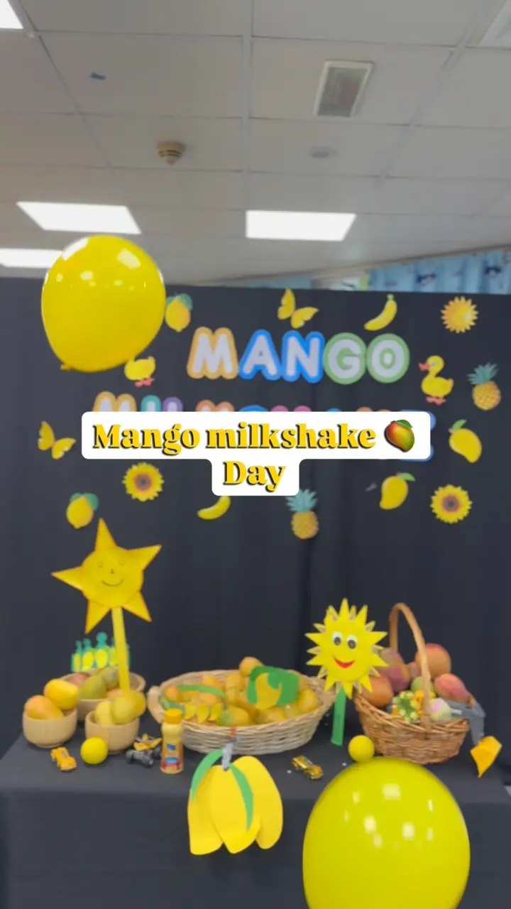 A yellow Mango Day display with fruit, balloons and a paper sun