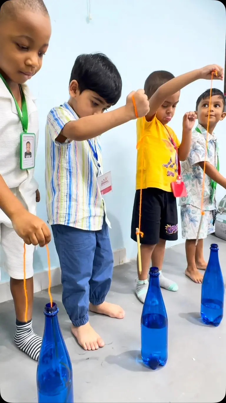 Children lowering a pen on a string into a bottle